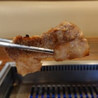 焼きあがった肉を箸で取る