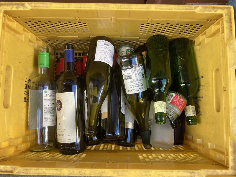 瓶を入れるコンテナの中に整理されて捨てられた、ワインの空き瓶